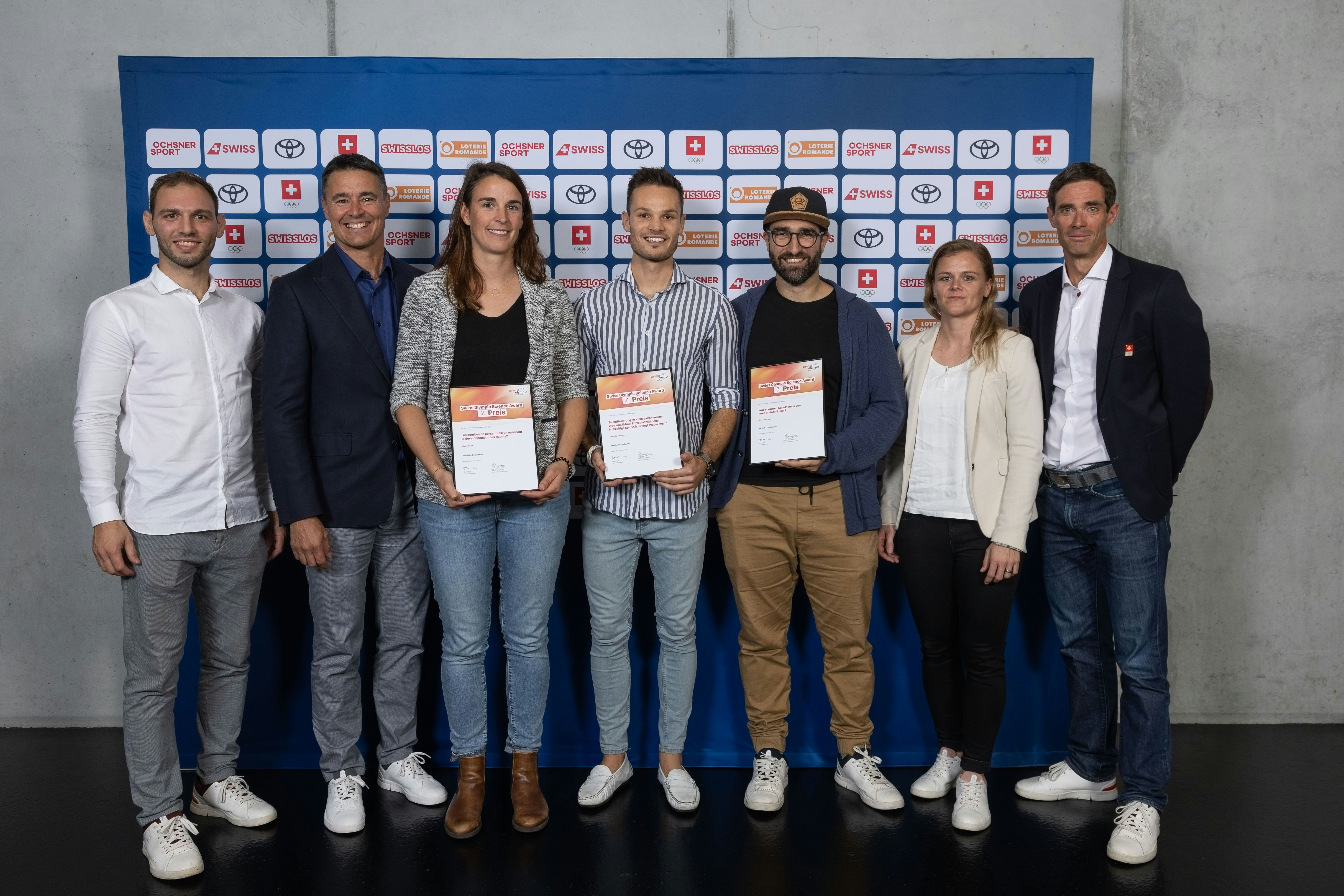 Die Sieger/innen des Swiss Olympic Science Award 2022 umrahmt von Vertretern der Ausrichterorganisationen. (von links) Joris Kuger (Swiss Olympic, Mark Wolf (Trainerbildung Schweiz), Marie Javet (2. Platz), Bryan Charbonnet (1. Rang), Dino Tartaruga (3. Rang), Nicole Gassmann (Swiss Olympic) und David Egli (Swiss Olympic).
Foto: BASPO / Ueli Känzig